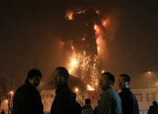 Obyvatelé Pekingu sledují mohutný požár způsobený ohňostrojem.