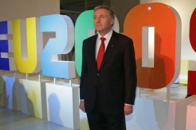Premiér Mirek Topolánek stojí před logem českého předsednictví.