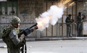 Izraelský voják vypouští slzný plyn proti demonstrantům.