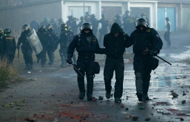 Policisté odvádějí zadrženého radikála po šarvátce na sídlišti Janov.