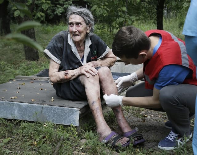 Zdravotník ošetřuje zraněnou ukrajinskou seniorku.