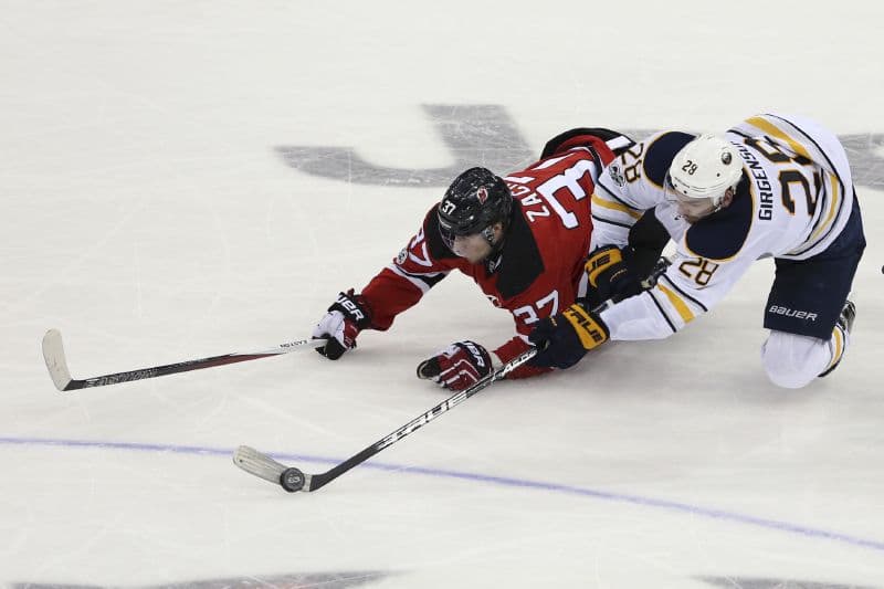 Pavel Zacha (v červeném) bojuje o puk v utkání NHL. 