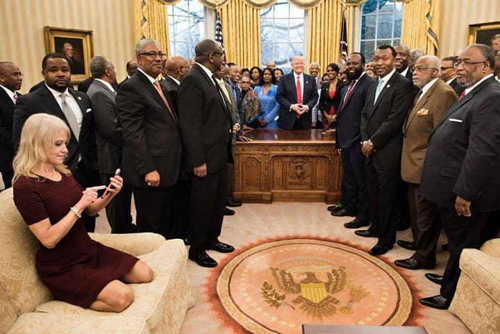 Kellyanne Conwayová klečí v botách na pohovce oválné pracovny.