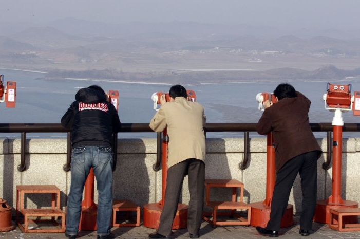 Turisté se v demilitarizované zóně u města Paju koukají dalekohledy na pobřeží na severokorejské město Kaepoong.