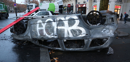 Posprejované ohořelé auto - následky demonstrací v Paříži.