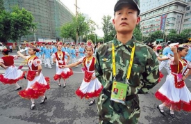 Folklór obyvatel z provincie Sin-ťiang. Pod dohledem uniforem.