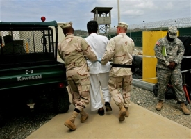 Vězeň a jeho strážní na Guantánamu.