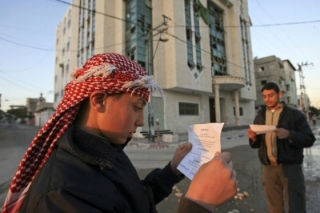 Palestinci čtou letáky. Výzývají je k opuštění oblasti před útokem.